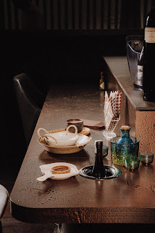 The image depicts a dimly lit interior setting of what appears to be a restaurant or bar in Thao Dien, Saigon. The counter is adorned with various ite