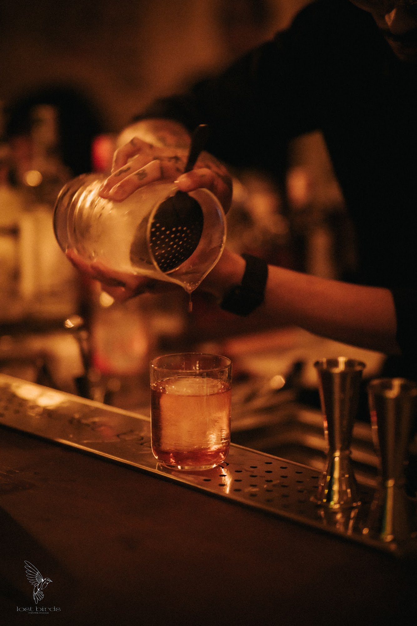 A bartender is pouring a drink into a glass at the bar in Thao Dien, Saigon.