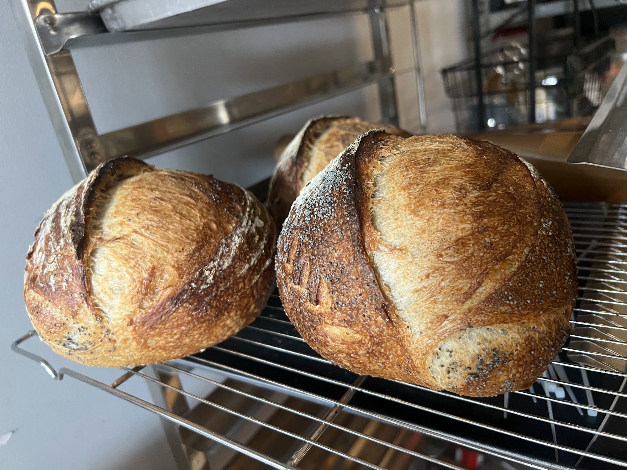 The image shows freshly baked bread on a cooling rack in what appears to be a professional kitchen or bakery setting.