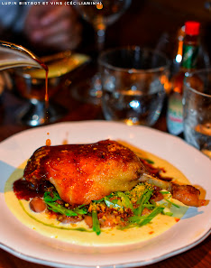 A plated dish featuring a piece of chicken topped with what appears to be a red sauce and garnished with green herbs, served on a bed of greens over a