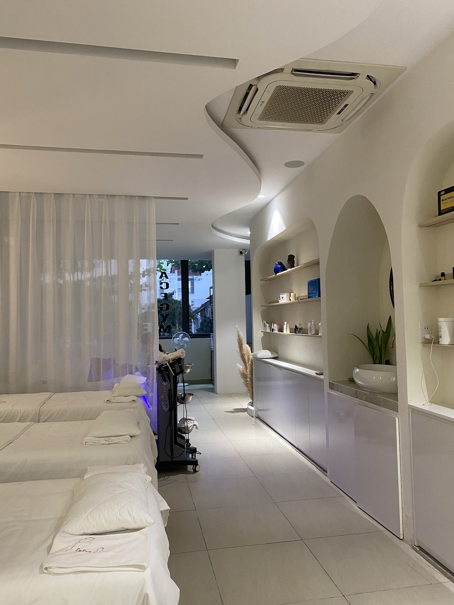 The image shows a modern and clean interior of what appears to be a spa or wellness center with multiple treatment beds lined up along one wall, each 