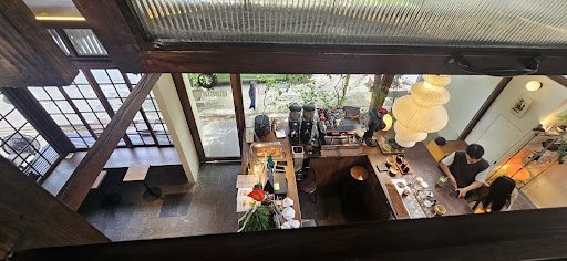 The image shows an interior view of a modern restaurant or bar located in Thao Dien, Saigon. The space is well-lit with natural light coming through l