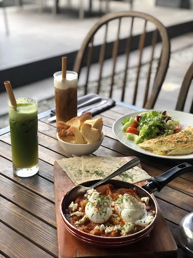 A dish with poached eggs and sauce served in a small skillet on a wooden board