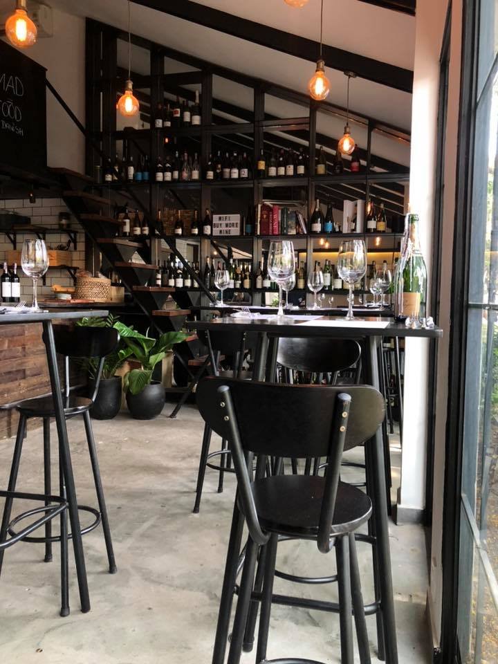 The image shows an interior view of a bar or restaurant setting in Thao Dien, Saigon. The space features industrial-style decor with exposed brick wal