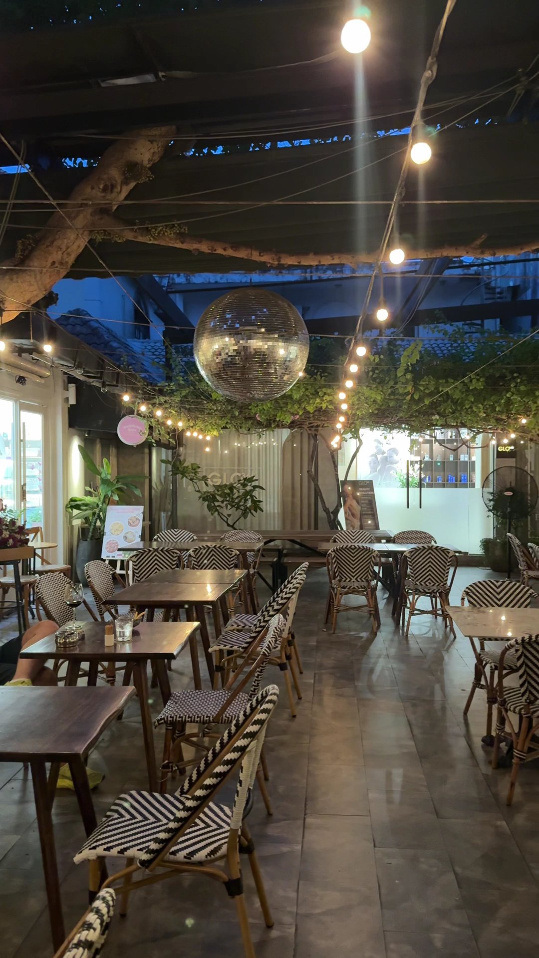 The image depicts an indoor dining area that appears cozy and inviting. The space is adorned with string lights hanging from the ceiling, creating a w
