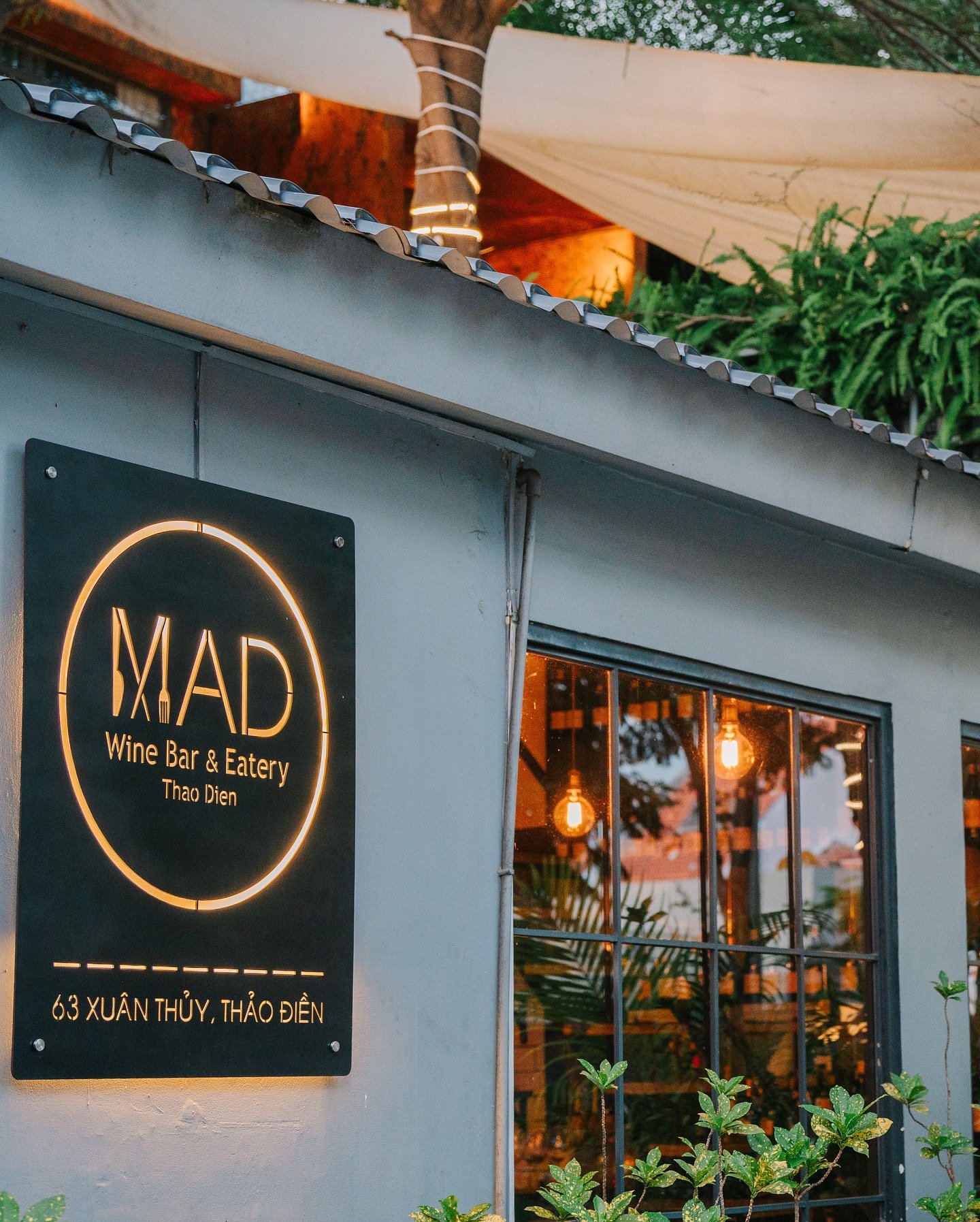 The image shows an exterior view of a wine bar and eatery named 'MAD' located in Thao Dien, Saigon.
