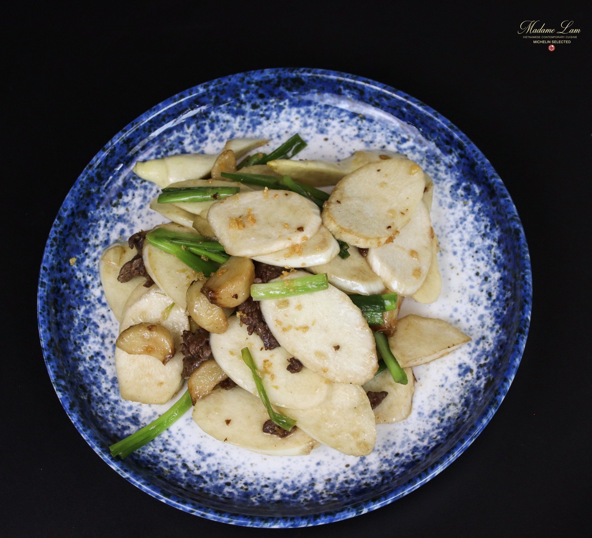 A plated dish featuring sliced mushrooms and green onions on a speckled blue plate.