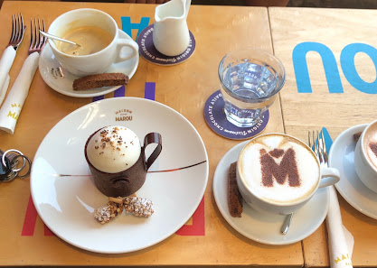 The image shows a table setting in what appears to be a café or restaurant named 'H&M'. There are various items on the table including two cups of cof