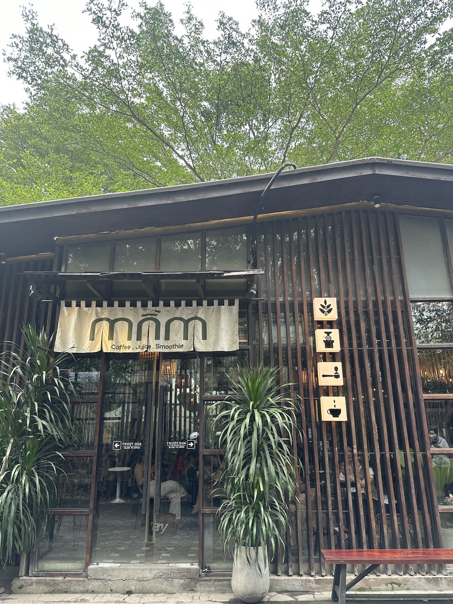 The image shows an exterior view of a coffee shop named 'mnm,' which offers Coffee, Juice, and Smoothies as indicated by the signage on its facade.