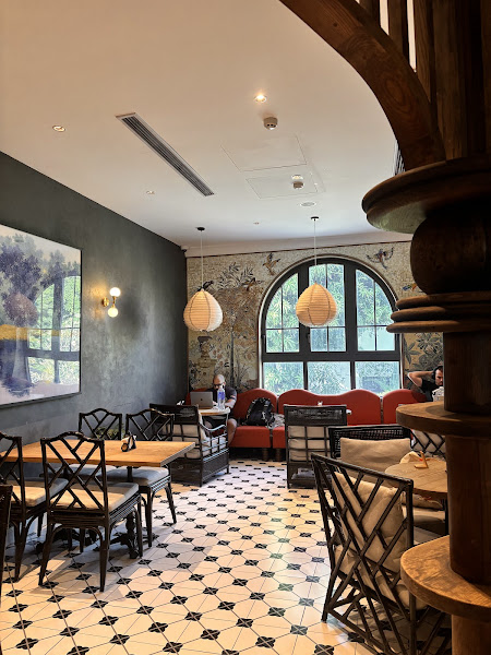 The image depicts the interior of a modern café or restaurant in Thao Dien, Saigon. It features a mix of contemporary and vintage elements. The space 