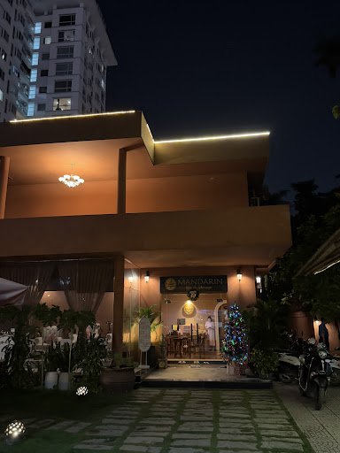 The image shows an exterior view of a restaurant named 'Mandarin' during nighttime. The establishment is illuminated with warm lighting, and there's a