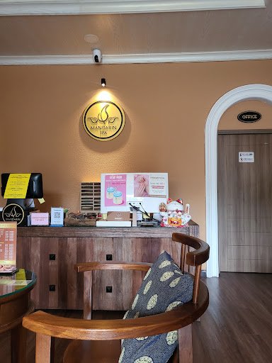 The image shows an interior view of a reception area in Thao Dien, Saigon. The decor is warm with wooden furniture and peach-colored walls. A round si