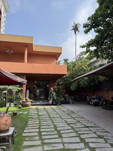 The image shows an exterior view of a building in Thao Dien, Saigon with a clear sky above and palm trees visible in the background.