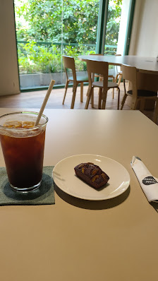 The image shows a table in an interior setting of Thao Dien, Saigon with a glass cup containing a dark beverage on the left and a plate with what appe