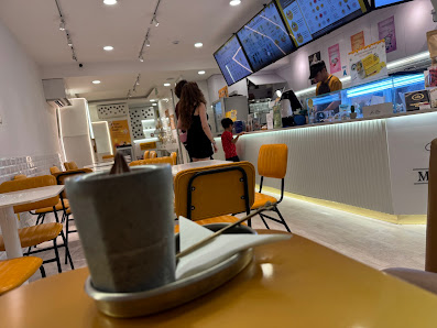 The image shows an interior view of a modern cafe or restaurant in Thao Dien, Saigon. The perspective is from the customer's viewpoint at one of the t