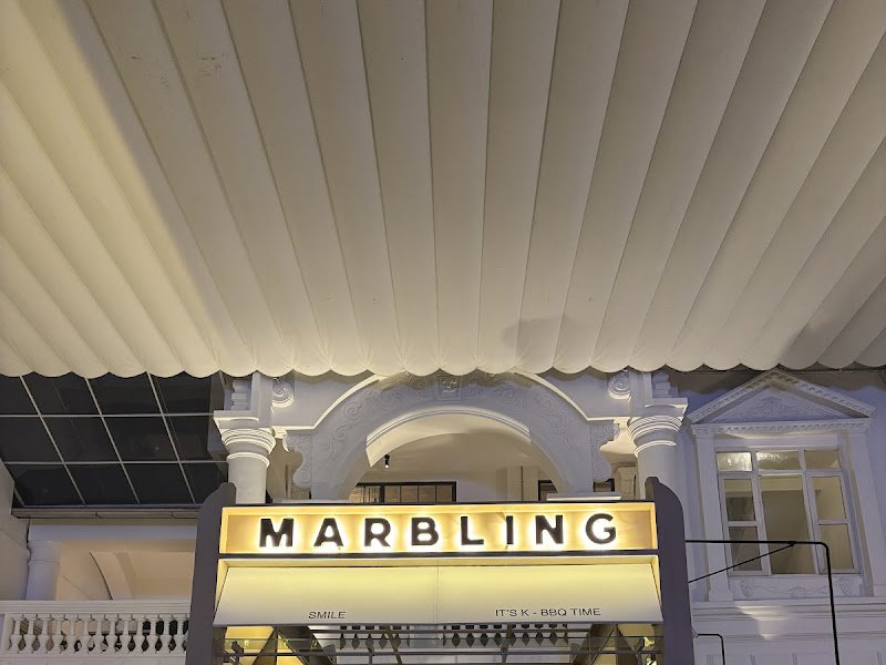 The image shows an exterior view of a venue named 'Marbling' at night with illuminated signage and architectural details visible.