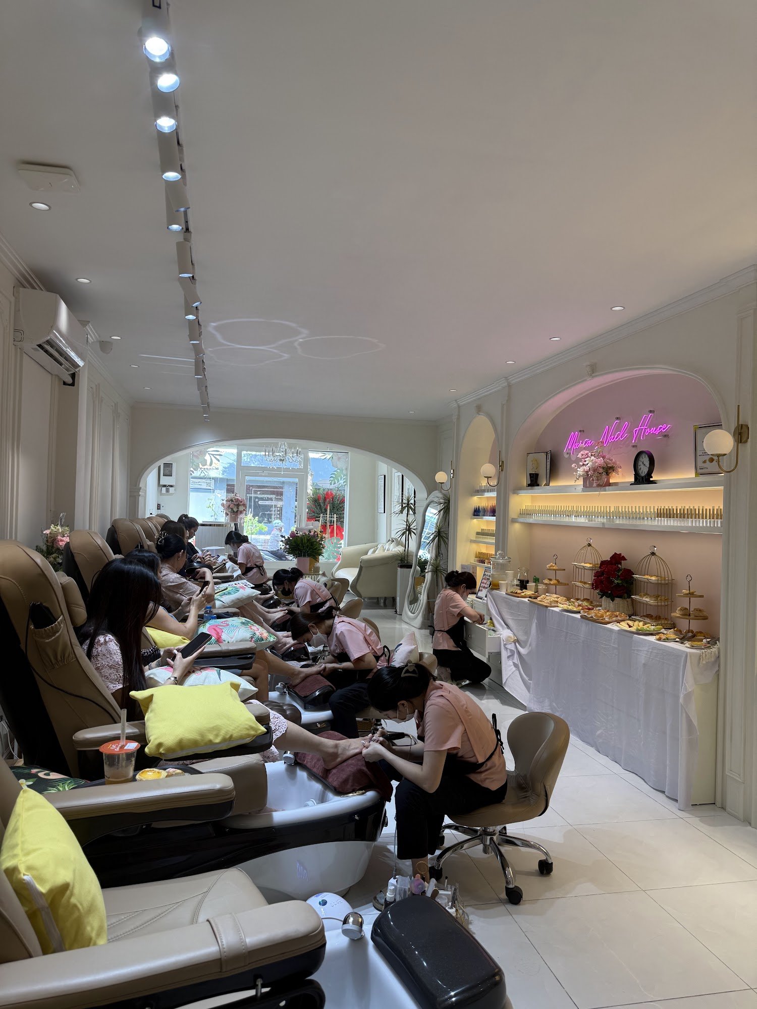 The image depicts an interior view of a modern nail salon or beauty parlor named 'Mia Nail House'. The space is well-lit with track lighting and featu