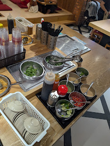 The image depicts a bustling kitchen counter in a restaurant in Thao Dien, Saigon. It features various cooking tools, including a stovetop with multip