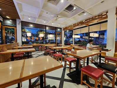 A modern restaurant interior in Thao Dien, Saigon, featuring wooden tables with red cushioned stools, black and white checkered flooring, large window