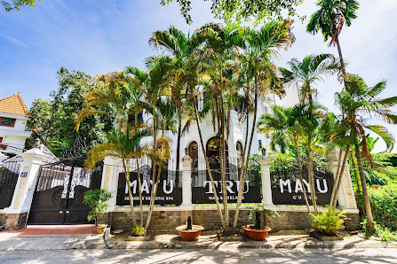 The image shows an exterior view of a building named 'MAYU TRU MAYU' with palm trees and potted plants in front, under clear skies.