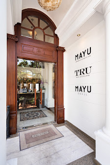 The image shows an entrance area of a venue named 'MAYU TRU MAYU CHILL'. The interior features wooden doors and trim, with the name displayed in large