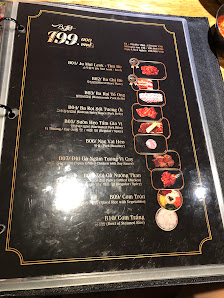 A black menu board with gold trim, displaying various dishes with prices (e.g., 199,000 VND), images of food items, and text in English. The menu feat