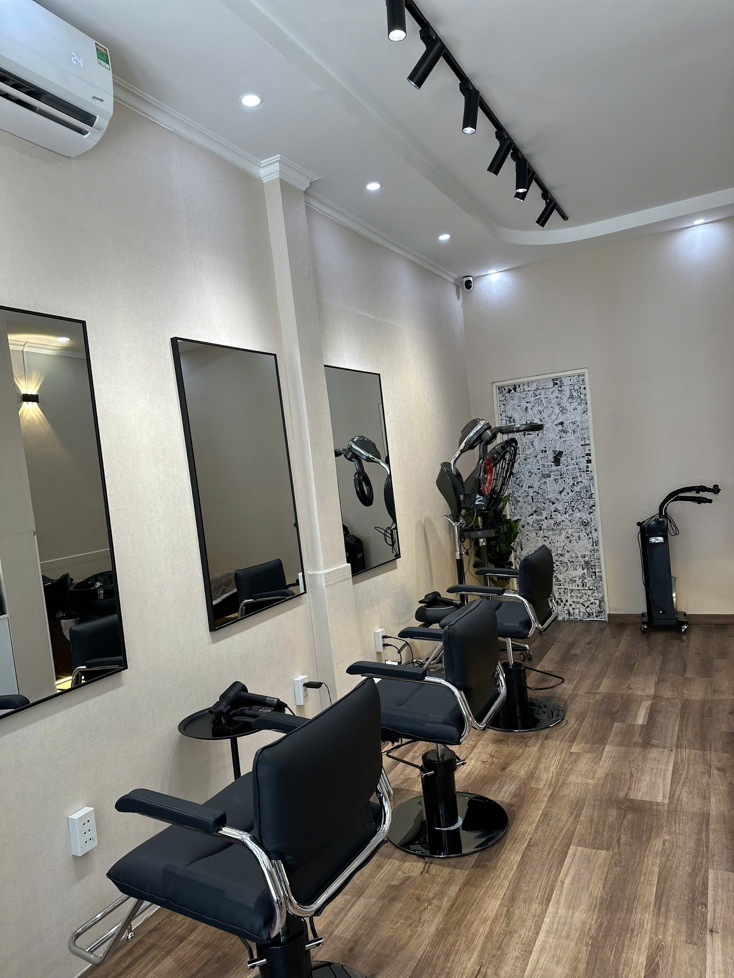 The image shows a modern hair salon interior featuring black chairs and mirrors on the wall.