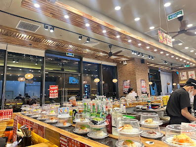 The image depicts the interior of a restaurant in Thao Dien, Saigon. It features a buffet-style setup with numerous food items displayed on trays and 
