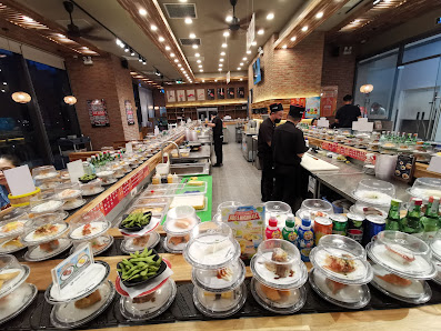 A bustling buffet restaurant interior in Thao Dien, Saigon, featuring long tables laden with various dishes in containers, including greens, rice dish