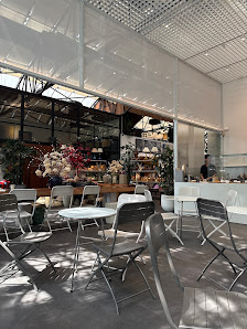 The image depicts an interior view of a modern cafe or bakery located in Thao Dien, Saigon. The space is well-lit with natural light streaming through