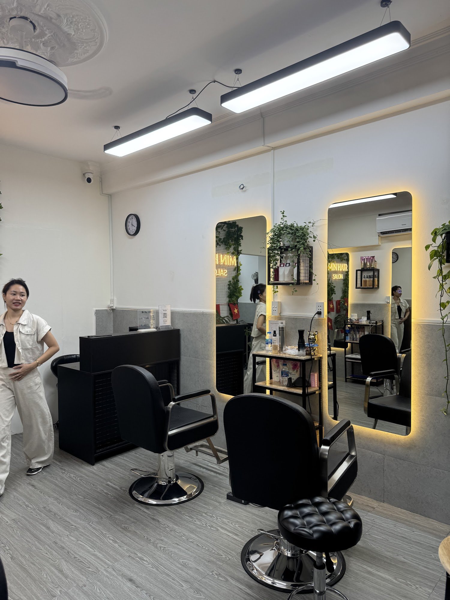 The image shows an interior view of a modern hair salon named 'Skin Hair Salon'. The space is well-lit with overhead lights and features two black bar