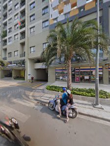 A street view showing a motorcycle parked on the side of the road in front of an apartment building with multiple floors and balconies.