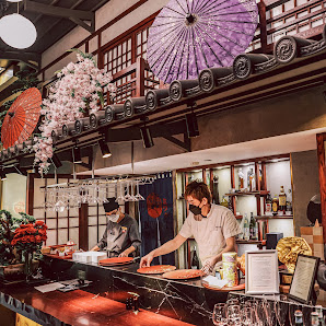 The image depicts an interior view of a restaurant or bar that has traditional Asian decor elements such as paper lanterns and parasols, with a modern