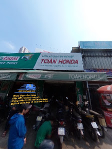 The image shows an exterior view of a Honda dealership named 'TOAN HONDA'. The establishment is located in Thao Dien, Saigon and has several motorcycl