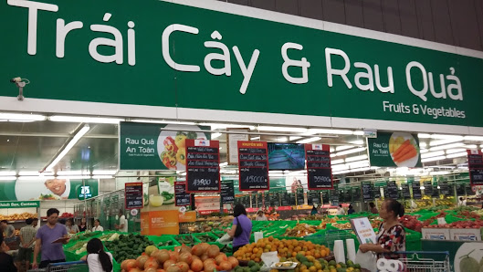 Interior view of a supermarket section in Thao Dien, Saigon, featuring a green sign with 'Trái Cây & Rau Quả' (Fruits & Vegetables) in Vietnamese and 