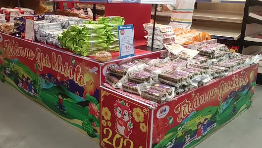 The image depicts a vibrant retail display within a supermarket or market in Thao Dien, Saigon. It features a colorful stall with Vietnamese text 'Tết