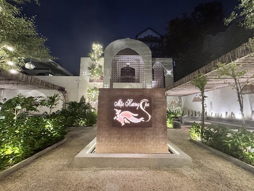 The image shows an exterior view of a restaurant named 'Old Henry Saigon' at night time with well-lit surroundings and greenery around the entrance.