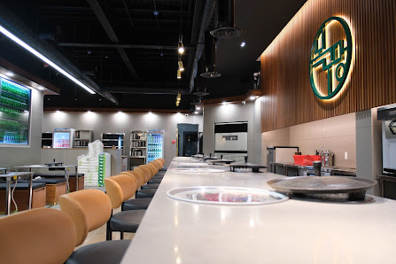 The image depicts the interior of a modern restaurant or café located in Thao Dien, Saigon. It features a long white counter with several round wooden