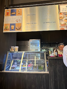 The image depicts the interior of a café or tea shop in Thao Dien, Saigon. Above a glass display case with compartments containing various items (like