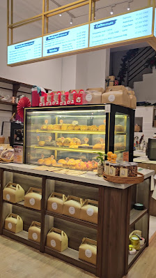 The image shows an interior view of a bakery or cafe in Thao Dien, Saigon with various pastries displayed on shelves and in glass cases.