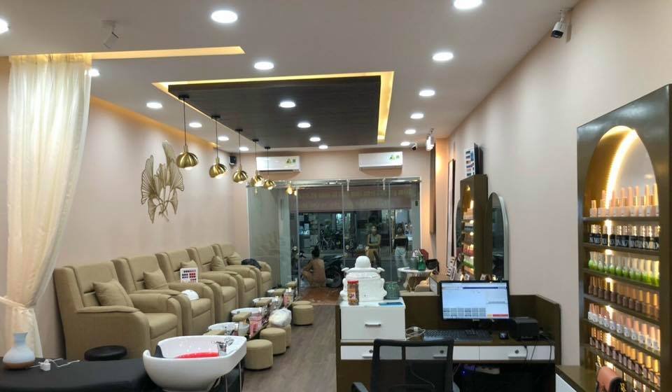 The image depicts an interior view of a modern nail salon or beauty parlor in Thao Dien, Saigon. The space is well-lit with recessed lighting and feat