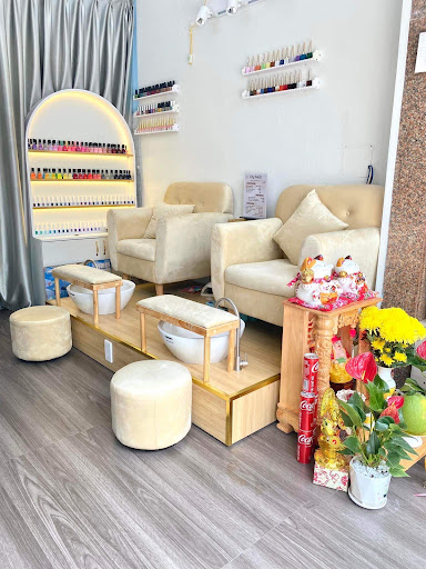 The image depicts a well-lit and neatly arranged nail salon or beauty parlor with various manicure stations equipped with chairs, foot baths, and shel
