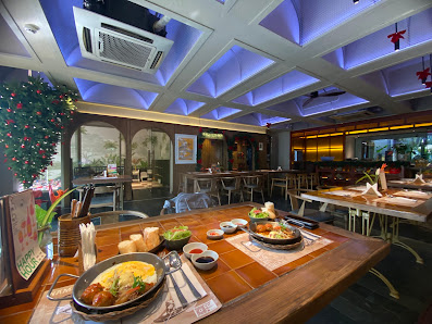 The image depicts the interior of a restaurant in Thao Dien, Saigon. It features a wooden table with various dishes, including a pan with food, small 
