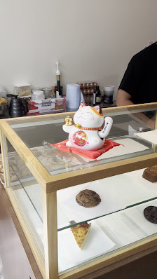 The image shows a display case in an interior setting at Thao Dien, Saigon with various items on it including what appears to be a Maneki-neko (beckon
