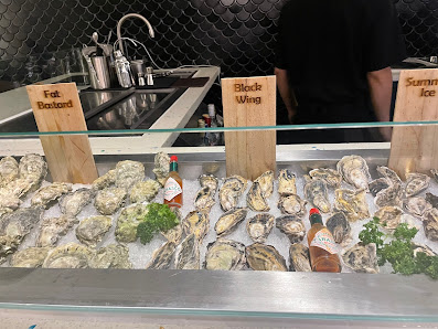 The image shows a seafood display at an establishment in Thao Dien, Saigon with various types of oysters and mussels on ice, accompanied by condiments