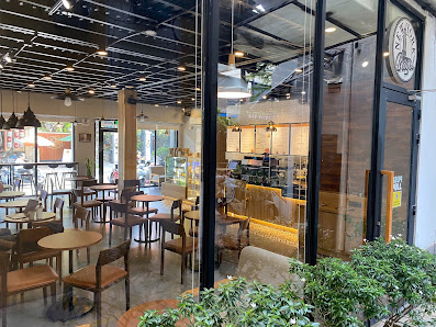 The image shows an interior view of a modern cafe or restaurant in Thao Dien, Saigon. The space features wooden tables and chairs with metal frames, a