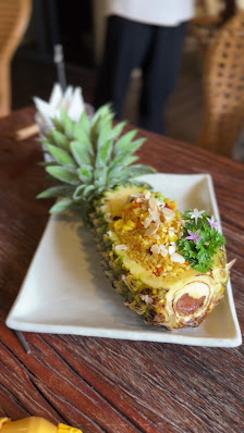 A creatively plated dish resembling a pineapple that appears to be stuffed and garnished on a white rectangular plate.