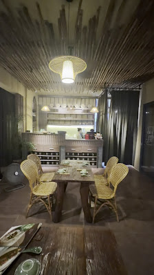 The image shows an interior view of a restaurant or dining area in Thao Dien, Saigon. The space features rustic wooden beams on the ceiling and dark-c