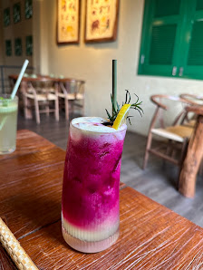 A colorful cocktail sits on a wooden table in what appears to be an indoor setting of Thao Dien, Saigon.