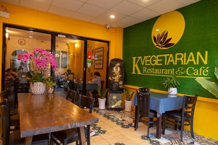 The image depicts the interior of K Vegetarian Restaurant & Café in Thao Dien, Saigon. The space features a vibrant yellow and green color scheme with